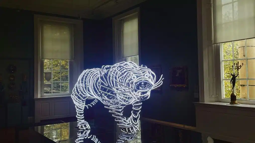 A glowing neon tiger sculpture displayed in a dimly lit room.
