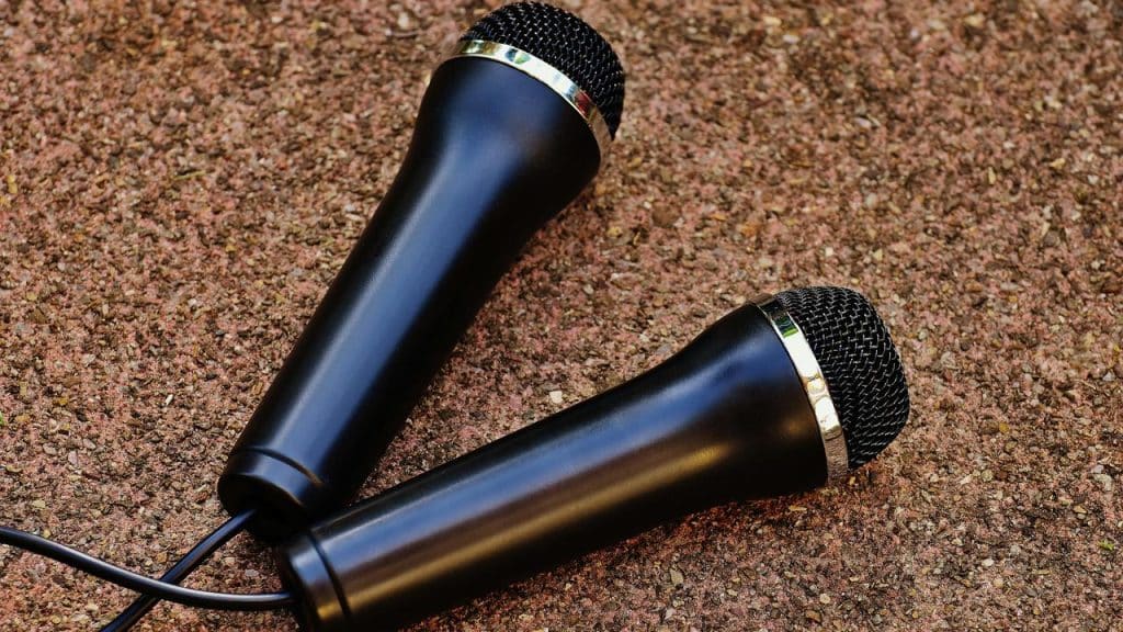 A pair of black microphones lying on a rough textured surface.