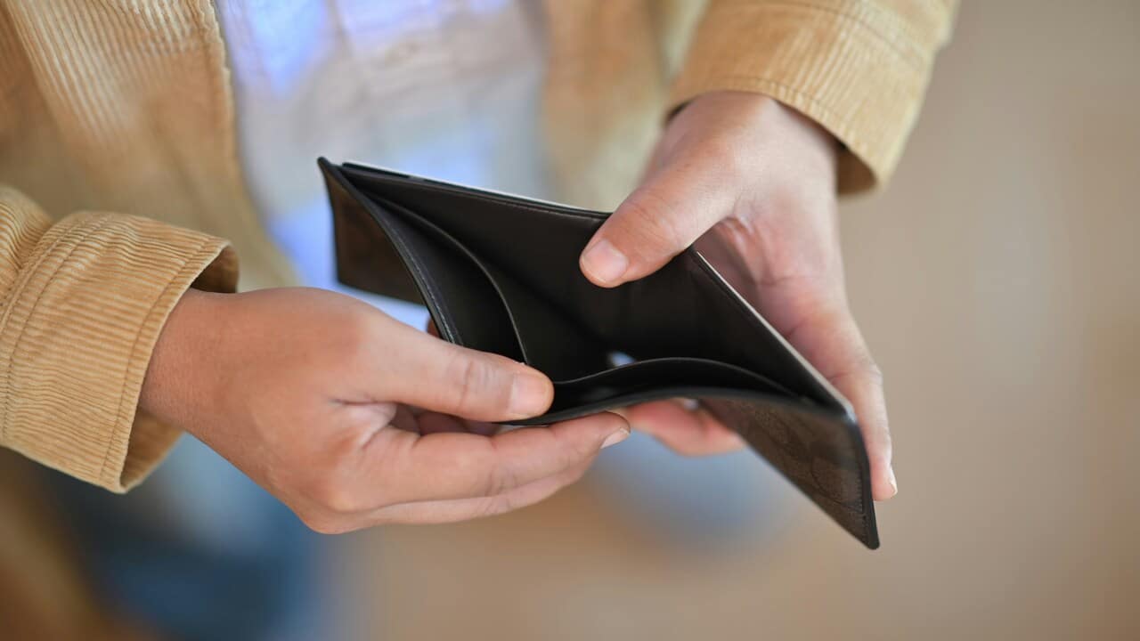 A man looking at his empty wallet.