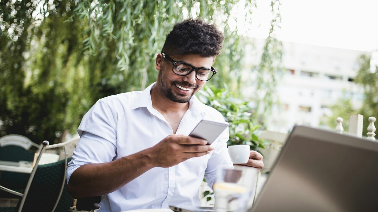 A man smiling while texting.