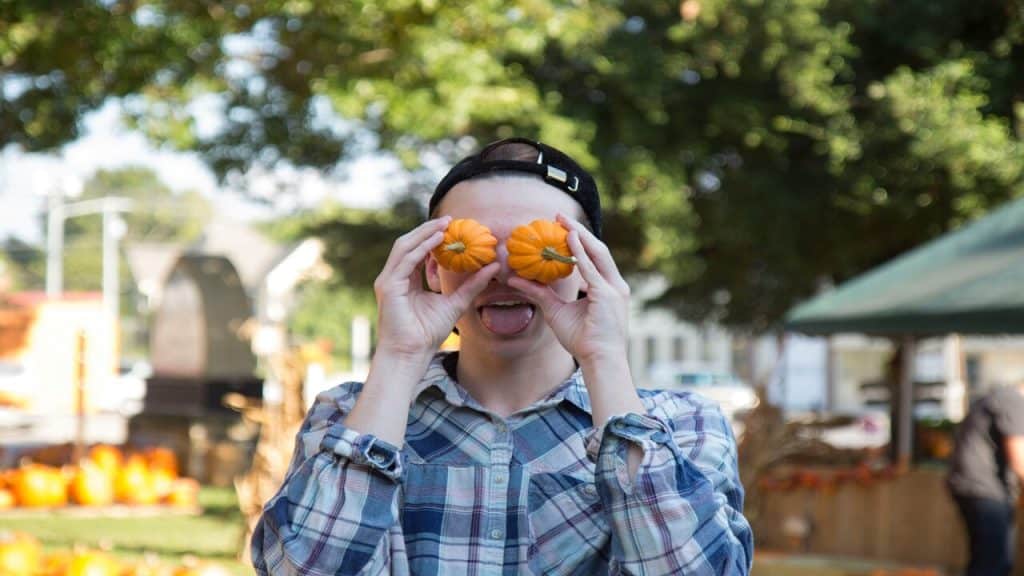 A man holding pumpkins over his eyes.