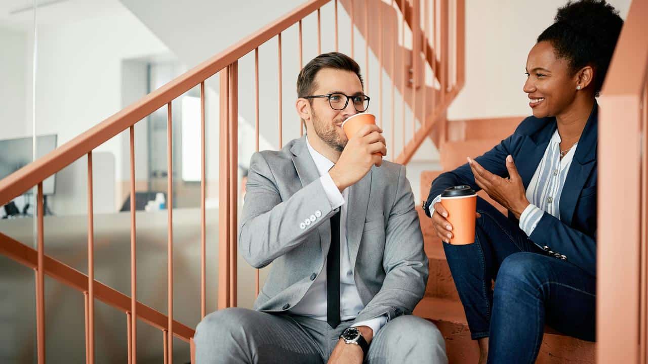 A man and woman sitting on stairs having coffee.