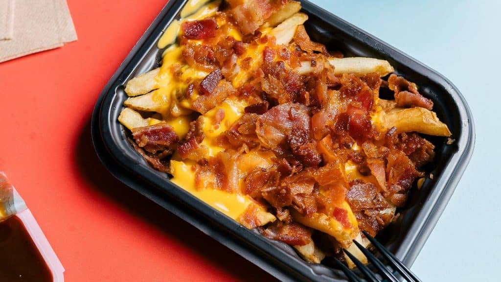 A tray of fries topped with cheese and bacon.