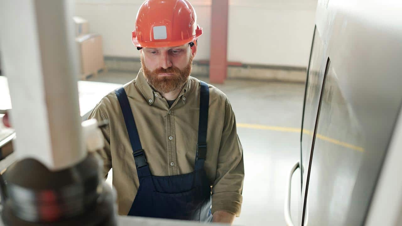 A construction worker wearing a red helmet operating machinery.