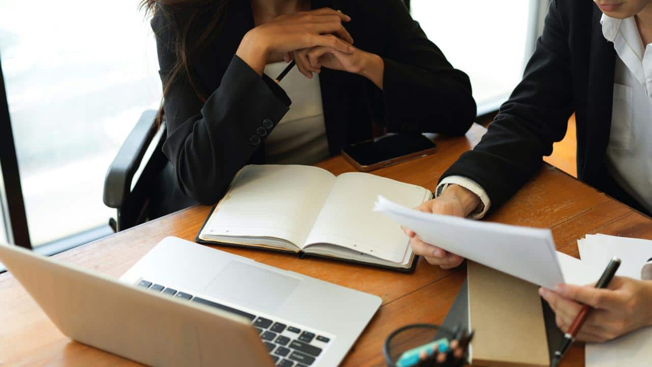 A person's hands holding papers in a meeting.