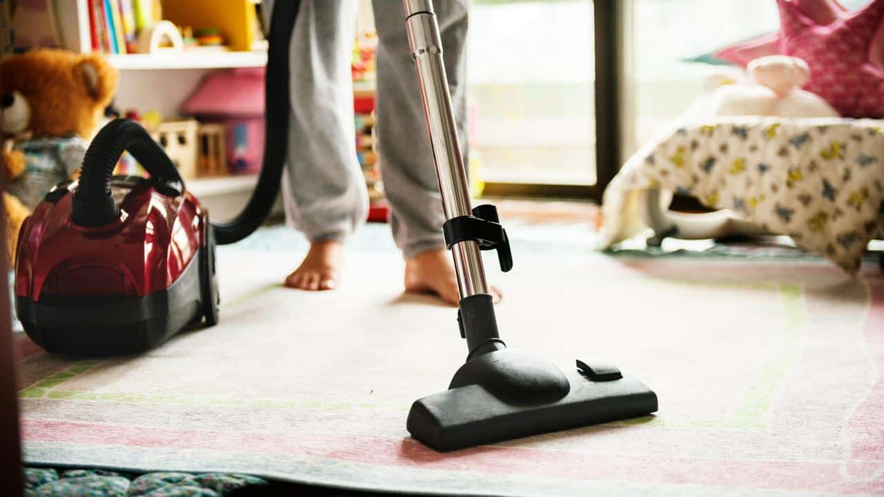 A person vacuuming a carpet in a room.