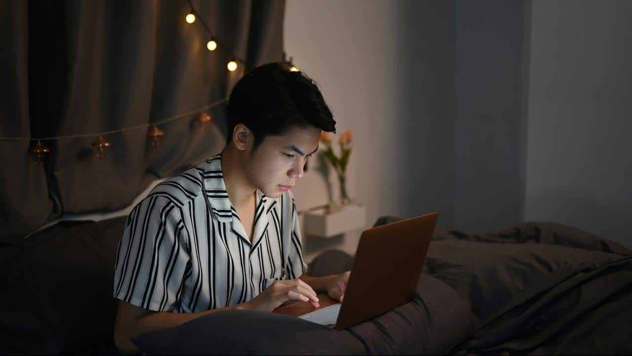 A person using a laptop on a bed at night.