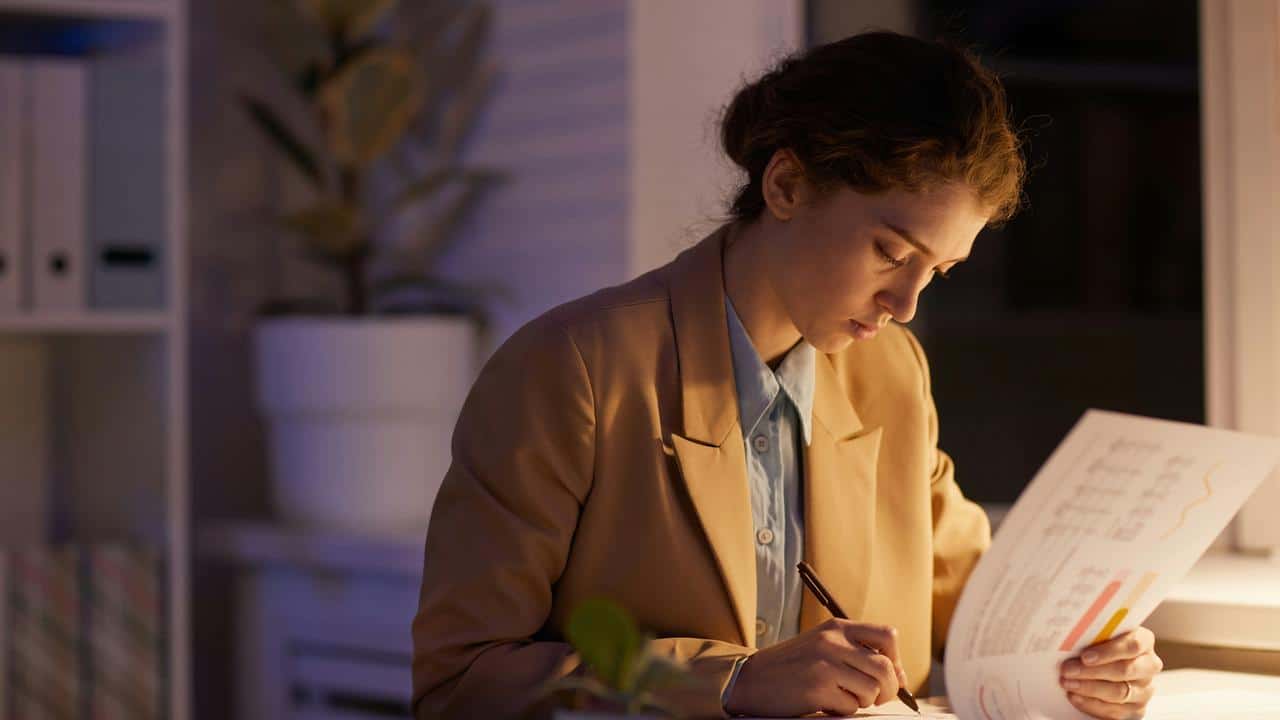 A woman working late reviewing documents.