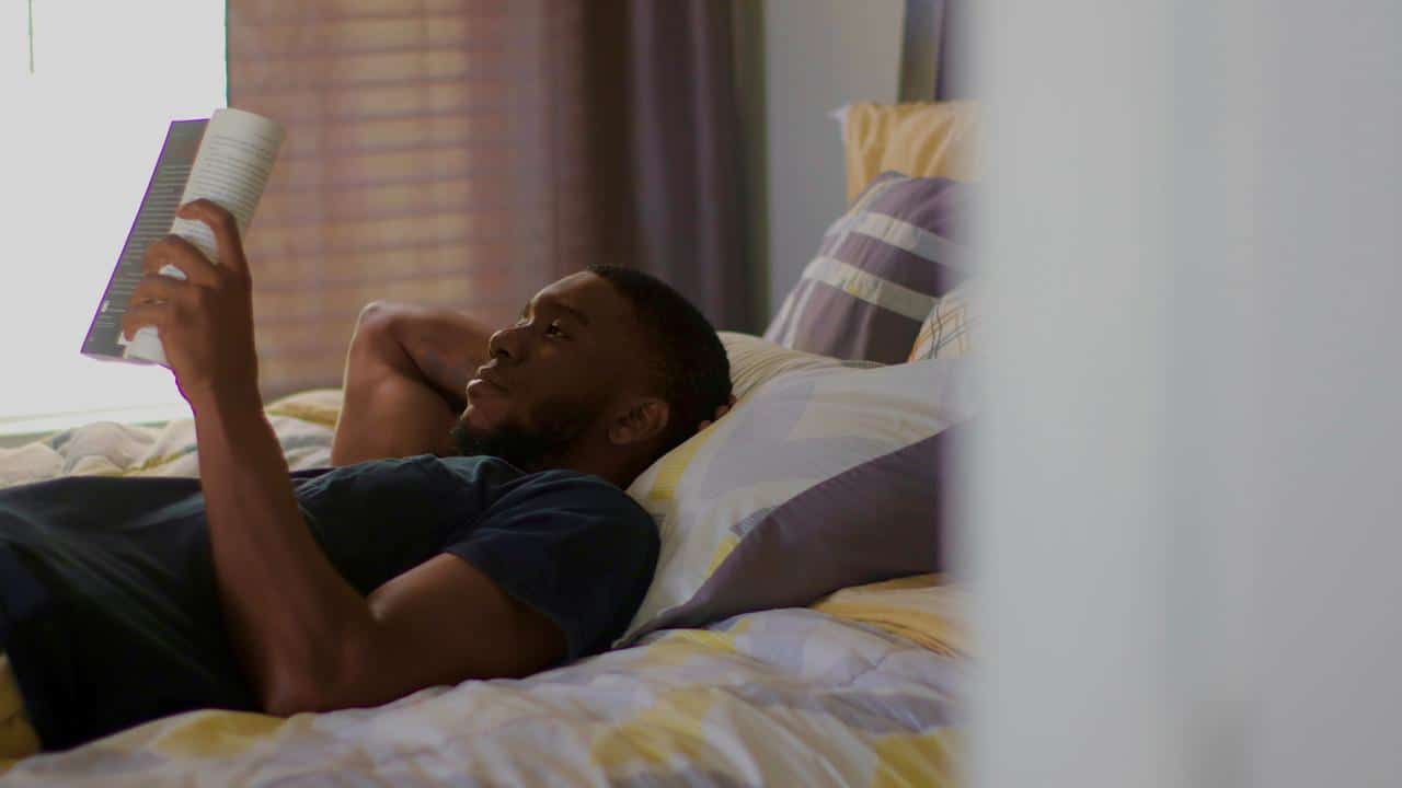 A person lying on a bed reading a book.