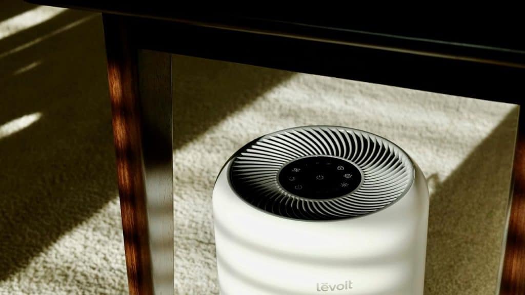 A white air purifier on a carpeted floor.