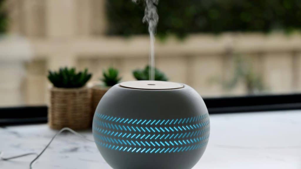 A round humidifier releasing mist on a table.