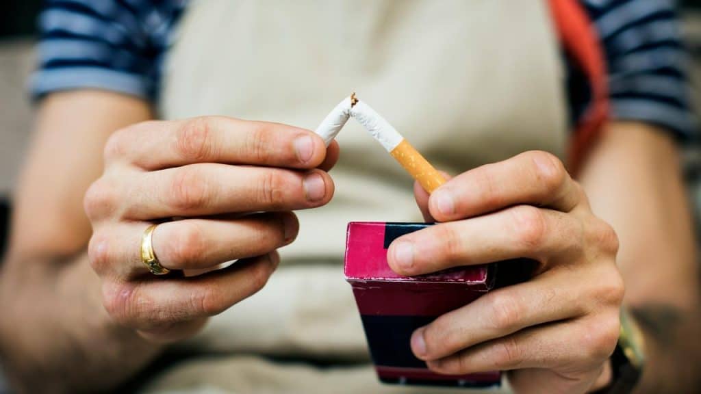 A person breaking a cigarette in half.