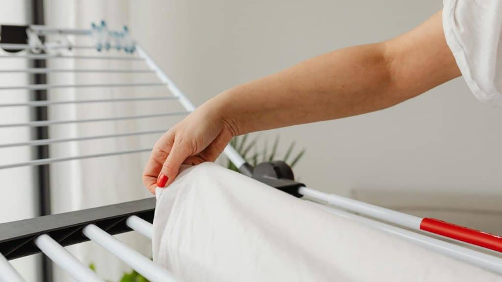 A person hanging laundry on a drying rack.