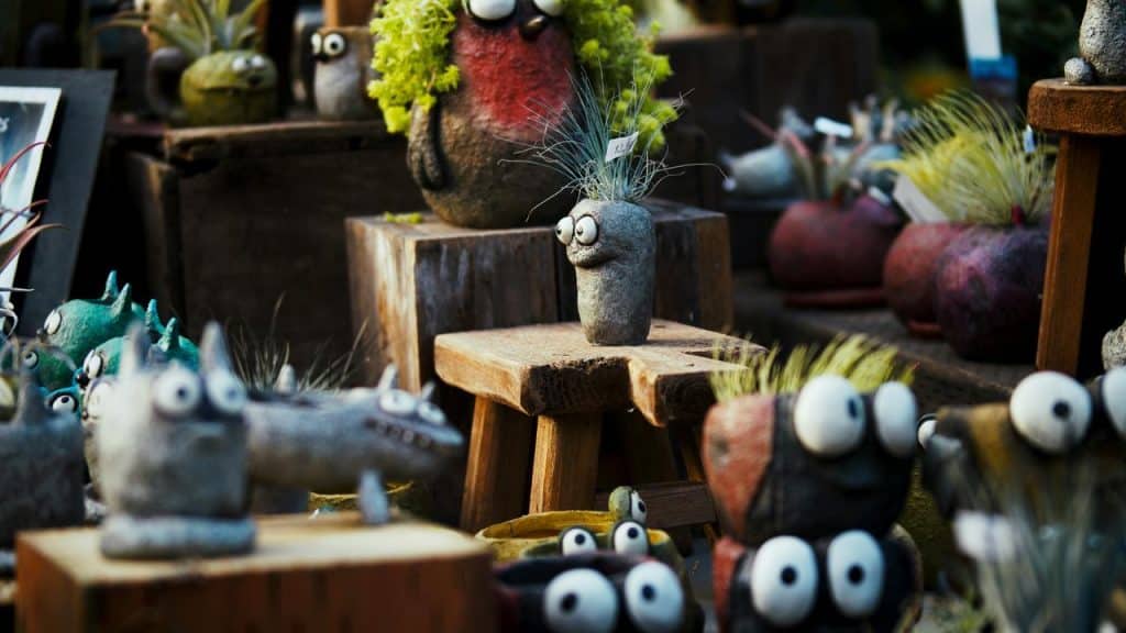 An assortment of quirky stone planters with googly eyes and plants on top.