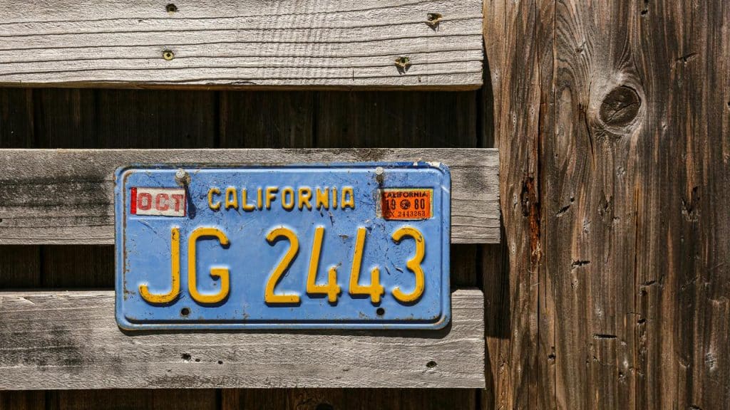 A vintage California license plate on a wooden fence.