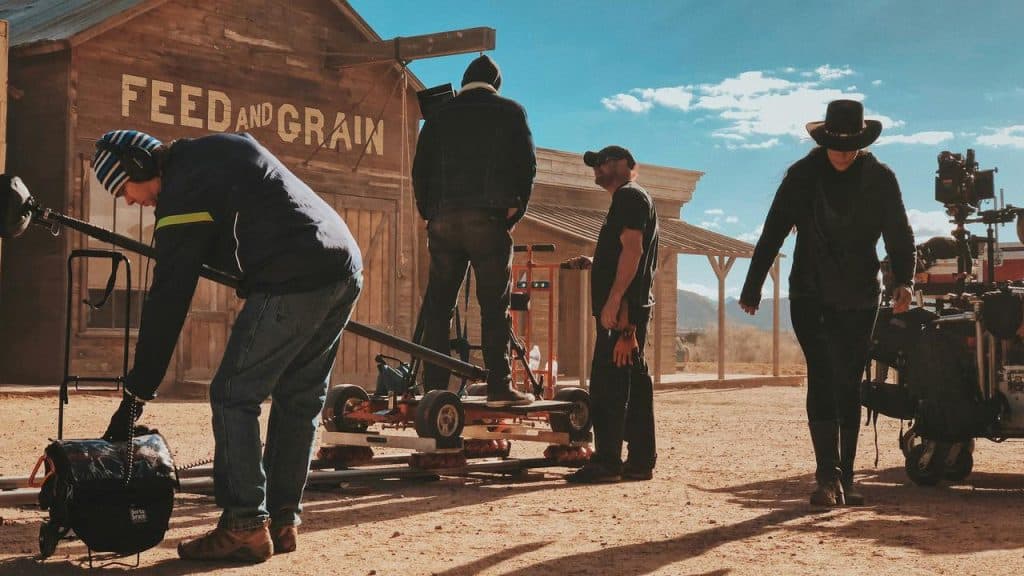 A film crew working on a set with western-style buildings.