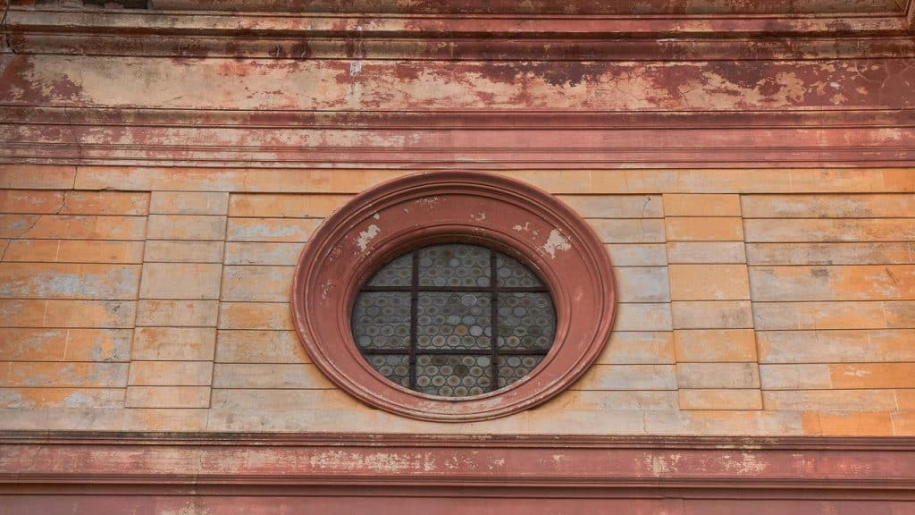 An old ship’s porthole on a weathered brick wall.