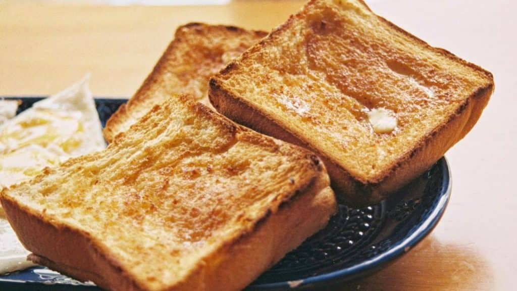 A plate with three slices of buttered toast.