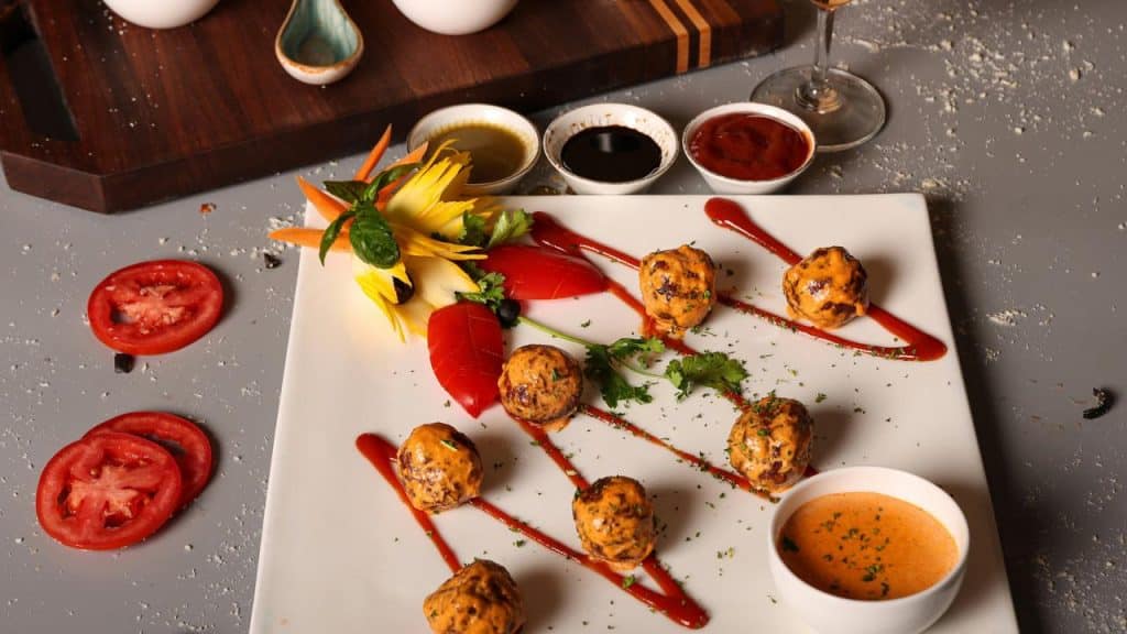 A gourmet plate of meatballs with sauce and vegetable garnish.