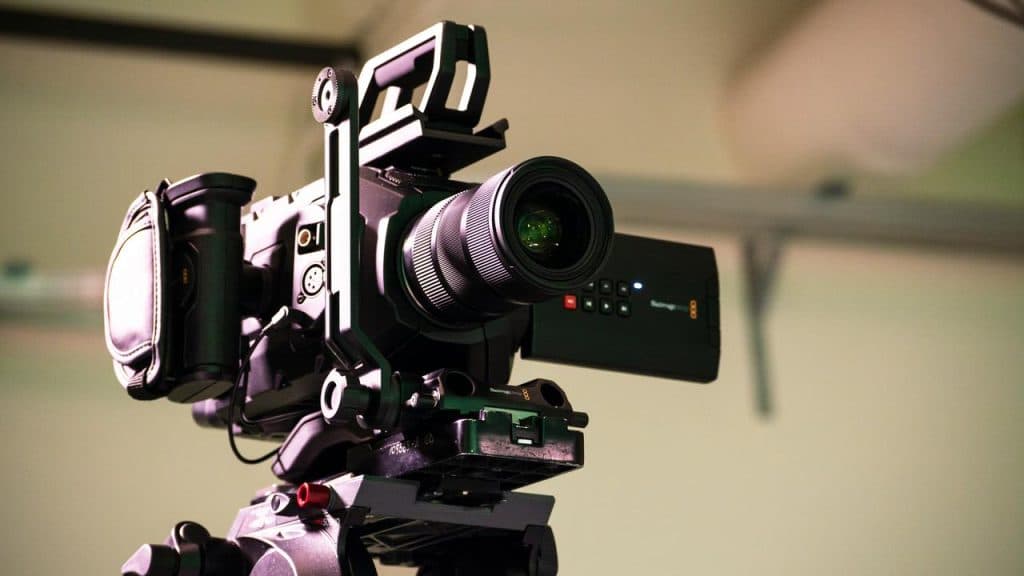 A professional video camera mounted on a tripod.