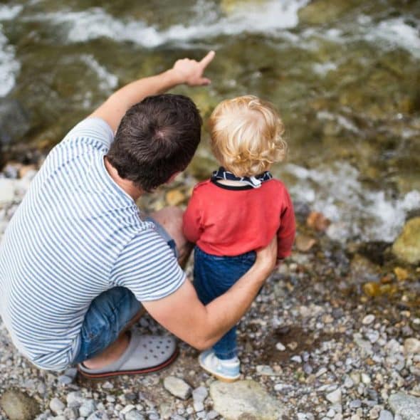 A father and his child looking at a flowing river.