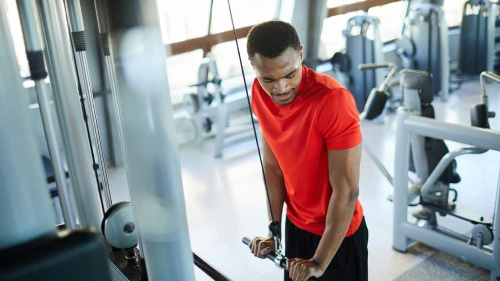 A man working out on a cable machine in a gym.