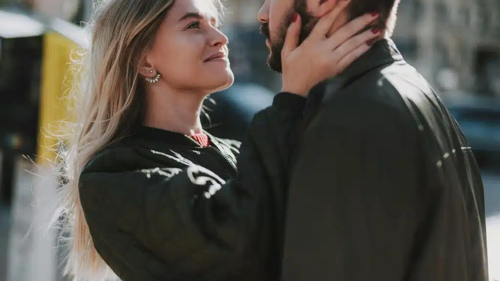 A woman gazing lovingly at a man while holding his face outdoors.