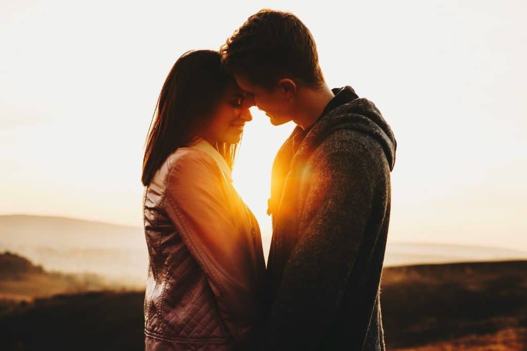 A man and woman kissing during sunset 