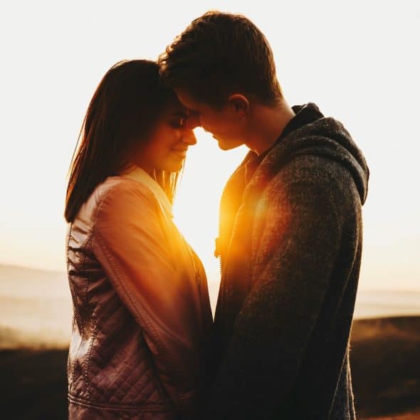 A man and woman kissing during sunset