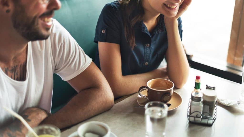 A smiling couple sitting at a diner table with drinks.