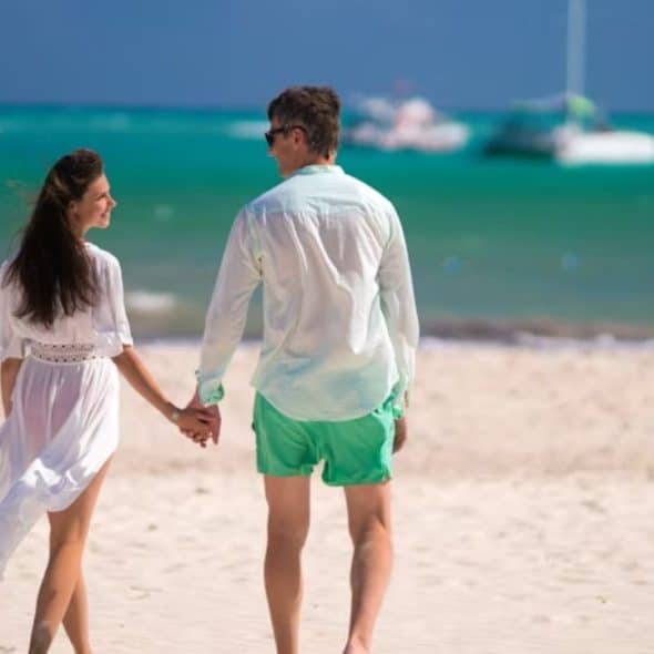 Couple walking barefoot along a quiet beach