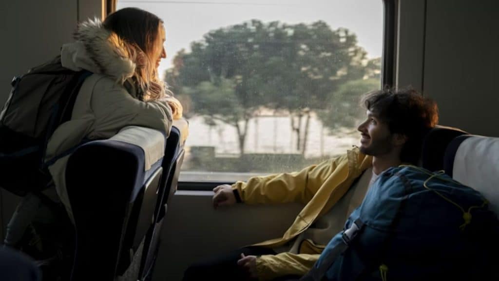 A Couple seated in train car looking out at scenic mountains