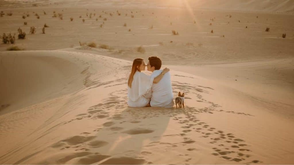A couple sitting in the desert under sunny sky.