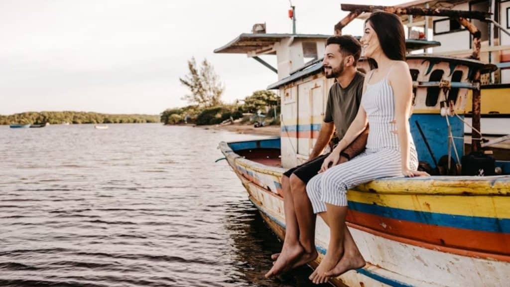 A couple enjoying the quiet from a houseboat on a calm lake.