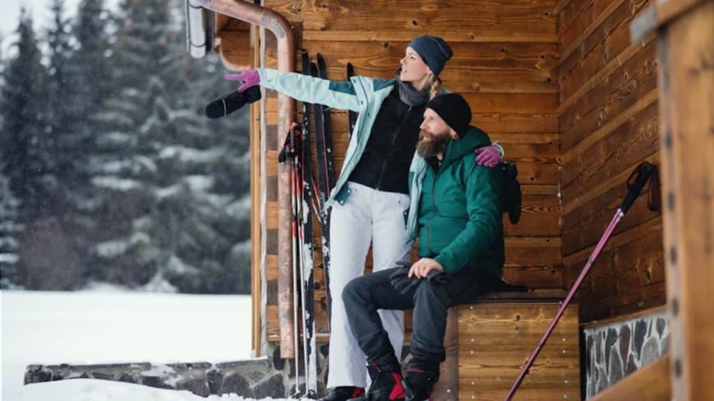 A couple outside a  lodge looking out at snowy mountains