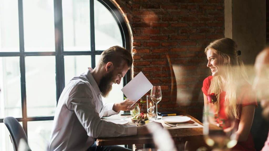 A smiling couple sitting at a restaurant table with menus.