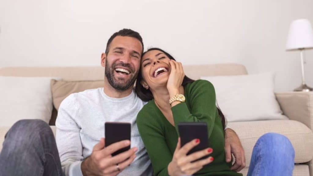 Man and woman laughing joyfully over something on their phones