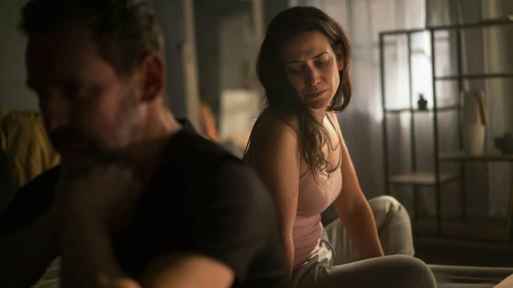 A frustrated man in the foreground and a sad woman in the background.