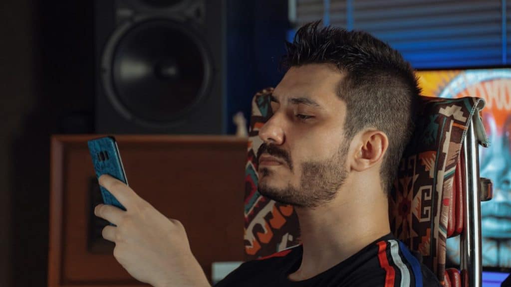 A man with a goatee and mustache is looking at his phone.