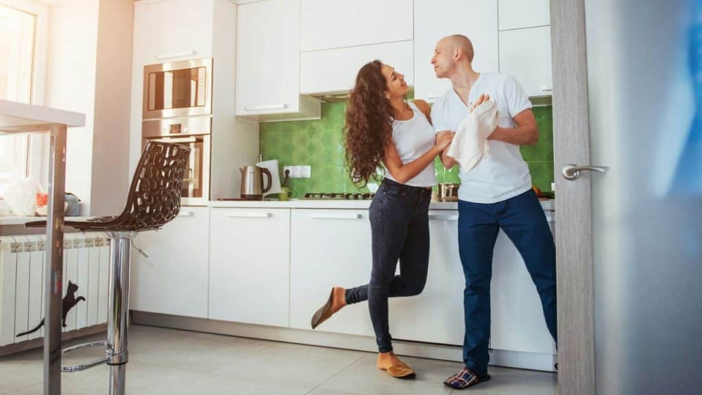 A happy couple standing and hugging in a bright, modern kitchen.