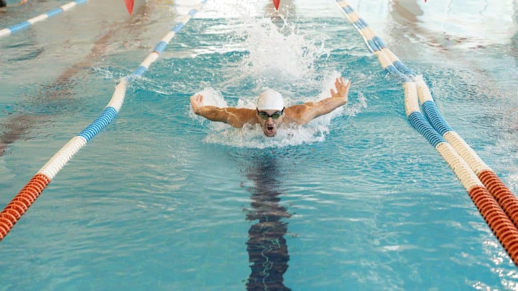 A swimmer doing the butterfly stroke in a pool.