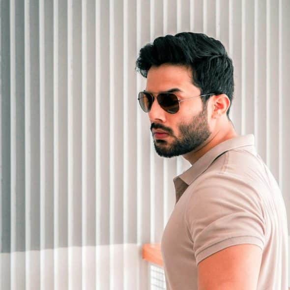 An adult man wearing sunglasses and a beige polo shirt indoors.