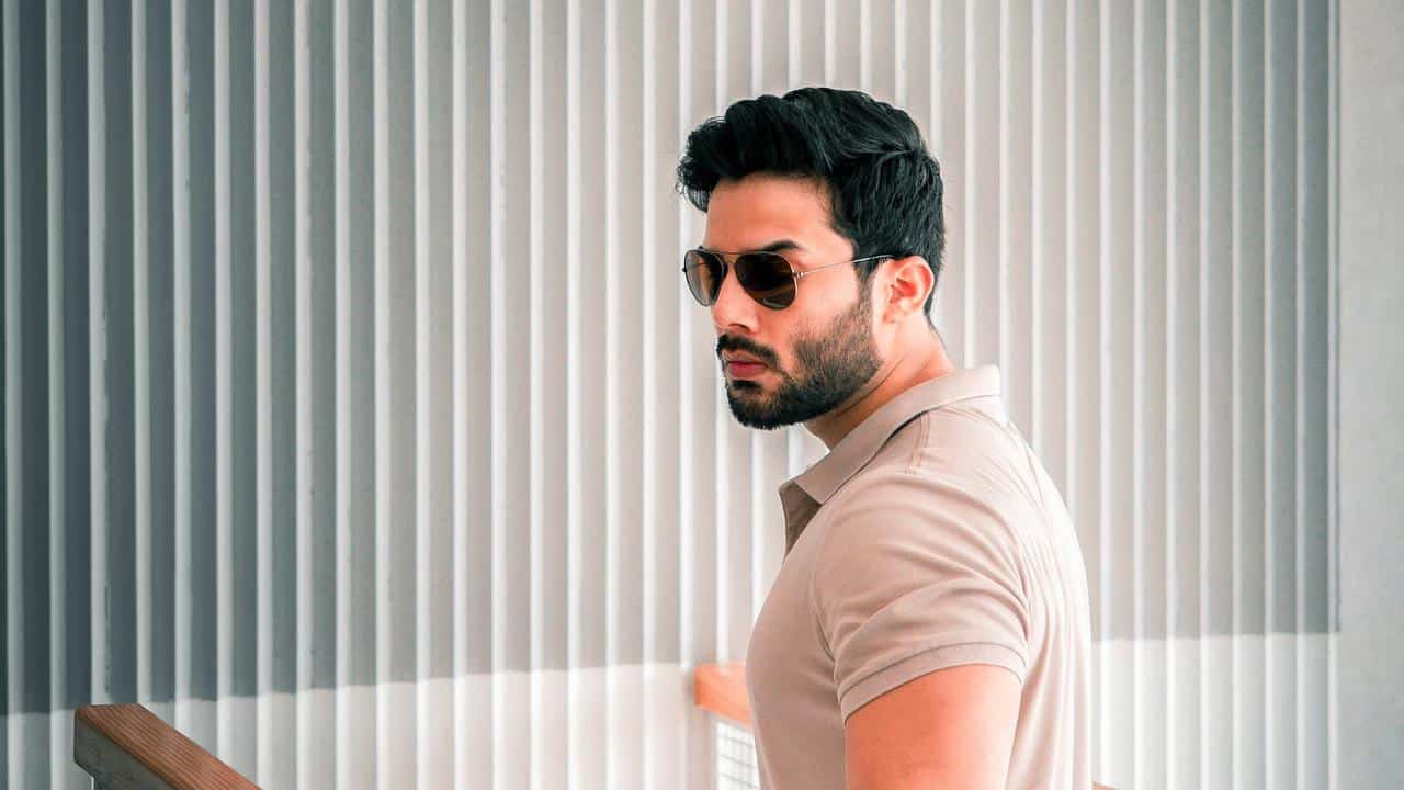 An adult man wearing sunglasses and a beige polo shirt indoors.