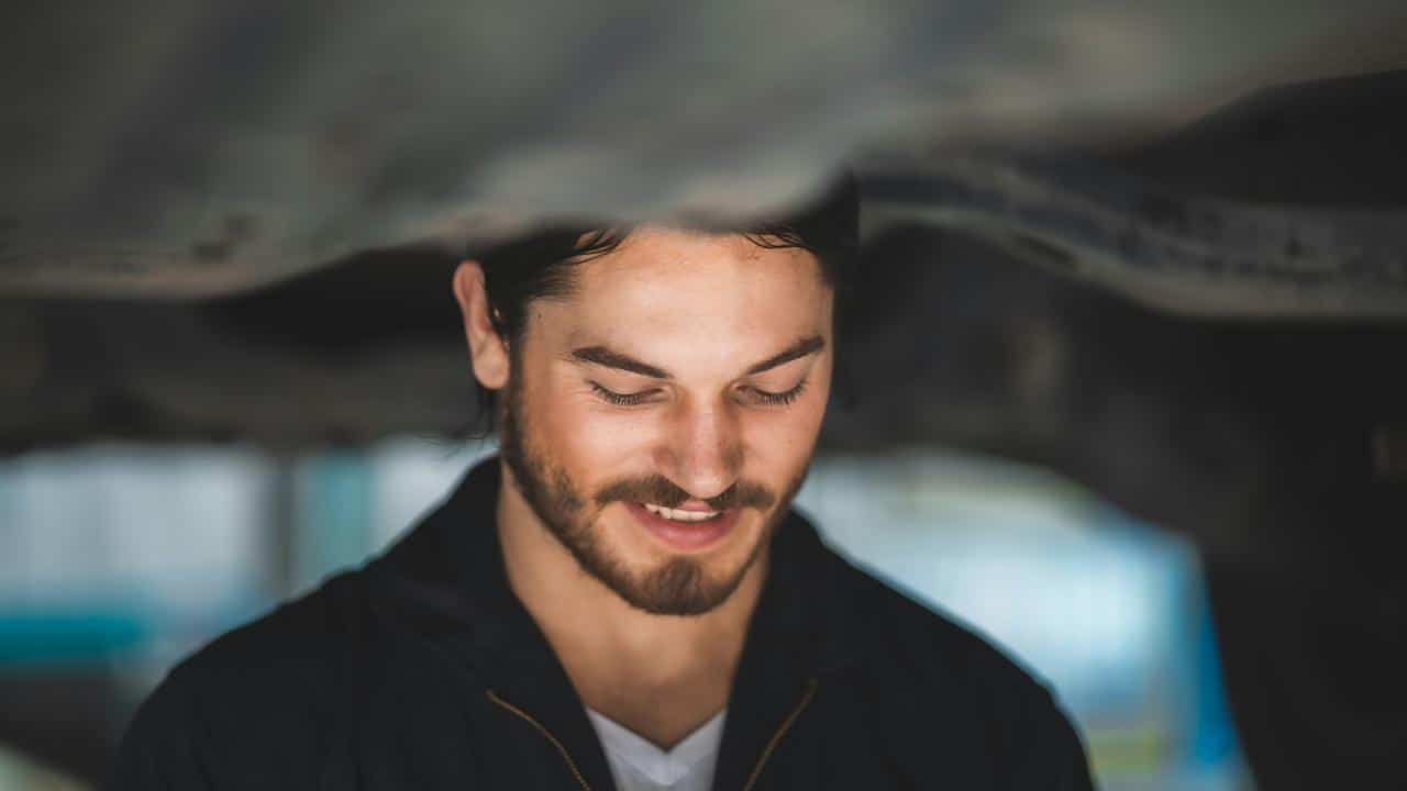 A smiling man with a beard looking down while working indoors.