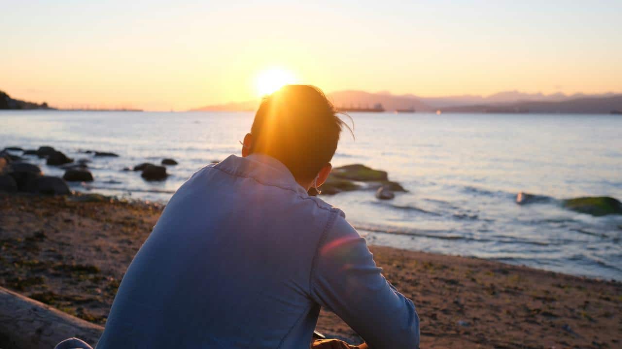 A person sitting on the beach watching the sunset over the ocean.