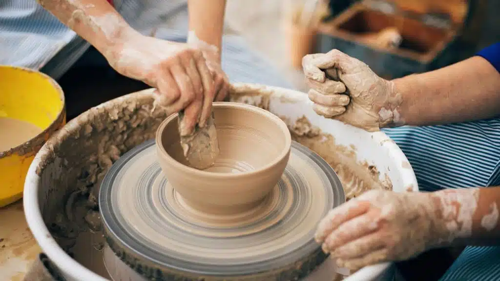 A potter shaping a clay bowl on a spinning wheel.