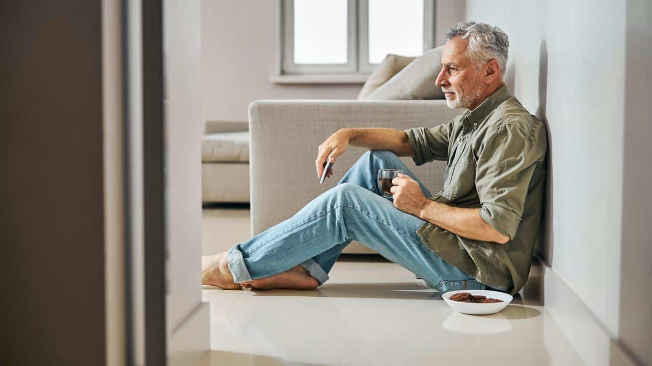 A grandfather sitting on the floor with coffee and cookies.