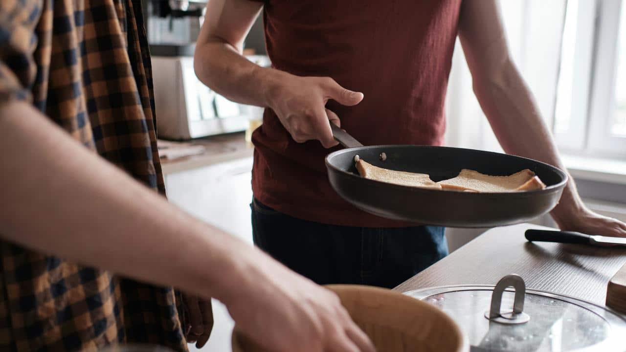 A father cooking toast in a pan with his child.