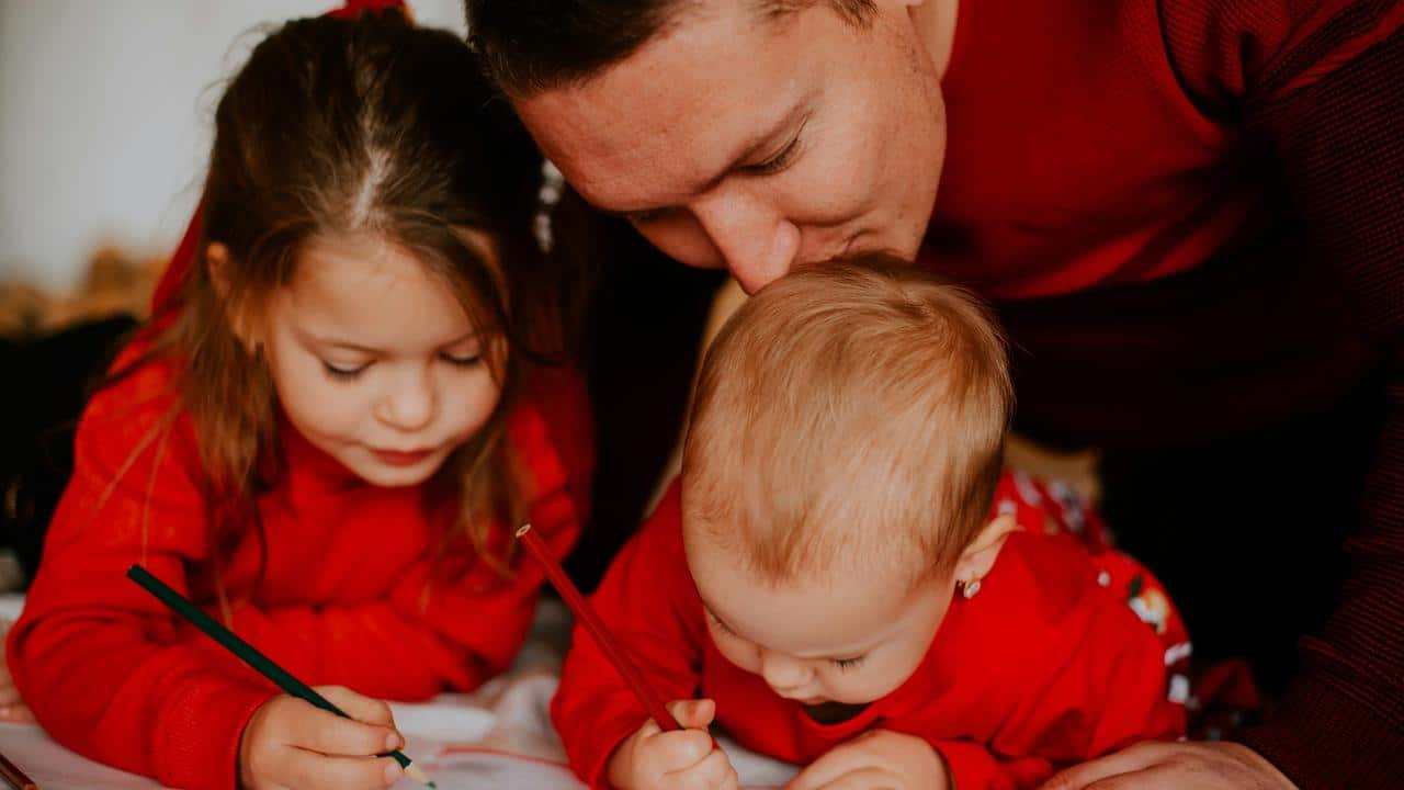 A father drawing with his two young children.