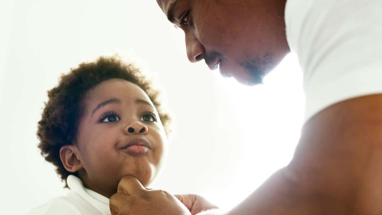 A father helping his child button a shirt.
